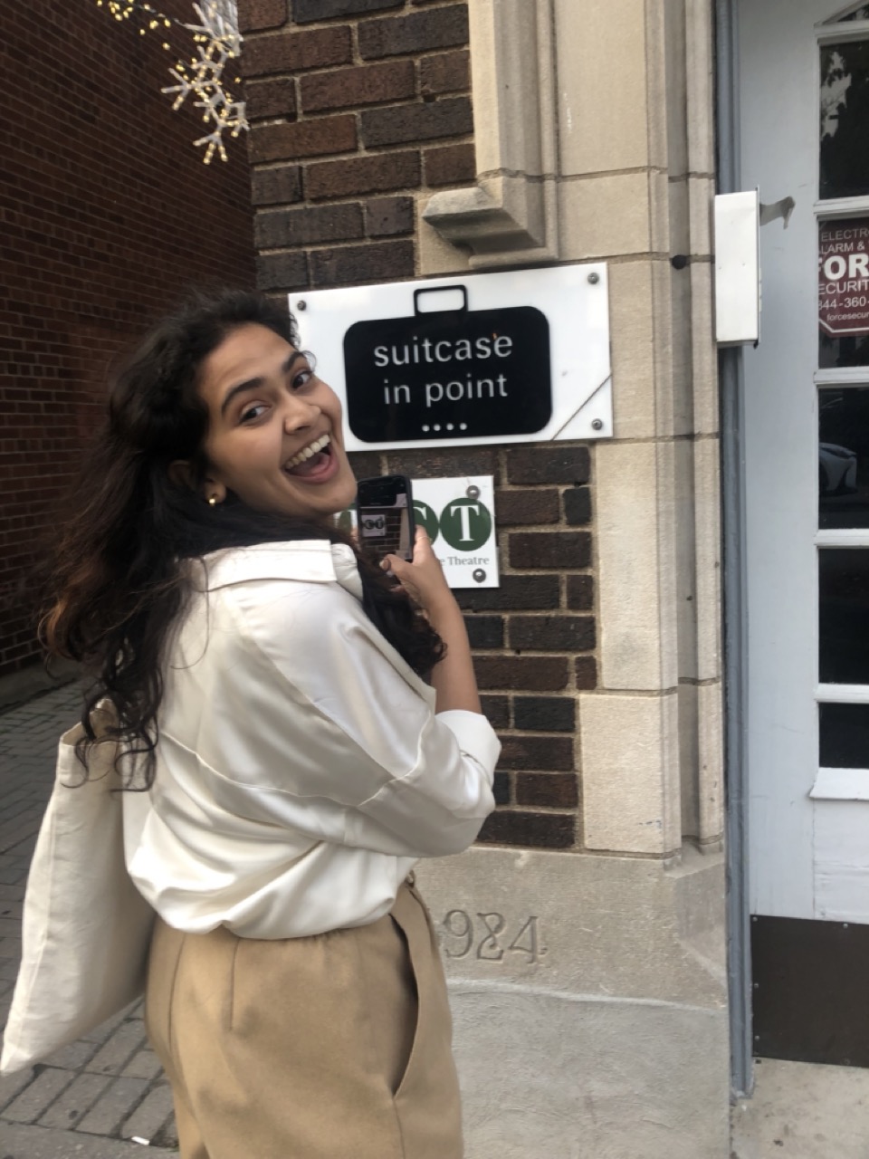 Arthi smiles looking at the sign which reads 'Suitcase in Point' 